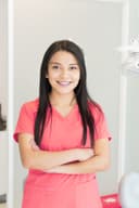 Woman dental professional in pink scrubs standing in a clinic