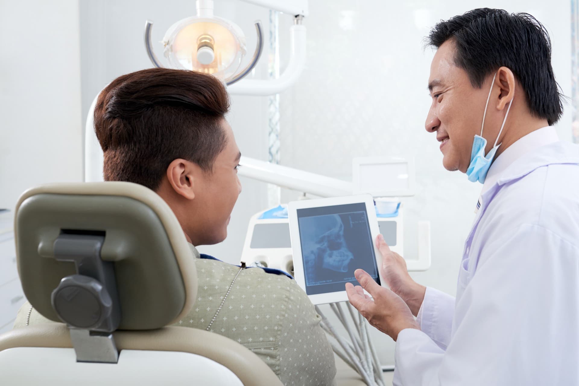 Dentist pointing out wisdom tooth position on a tablet X-ray with the patient